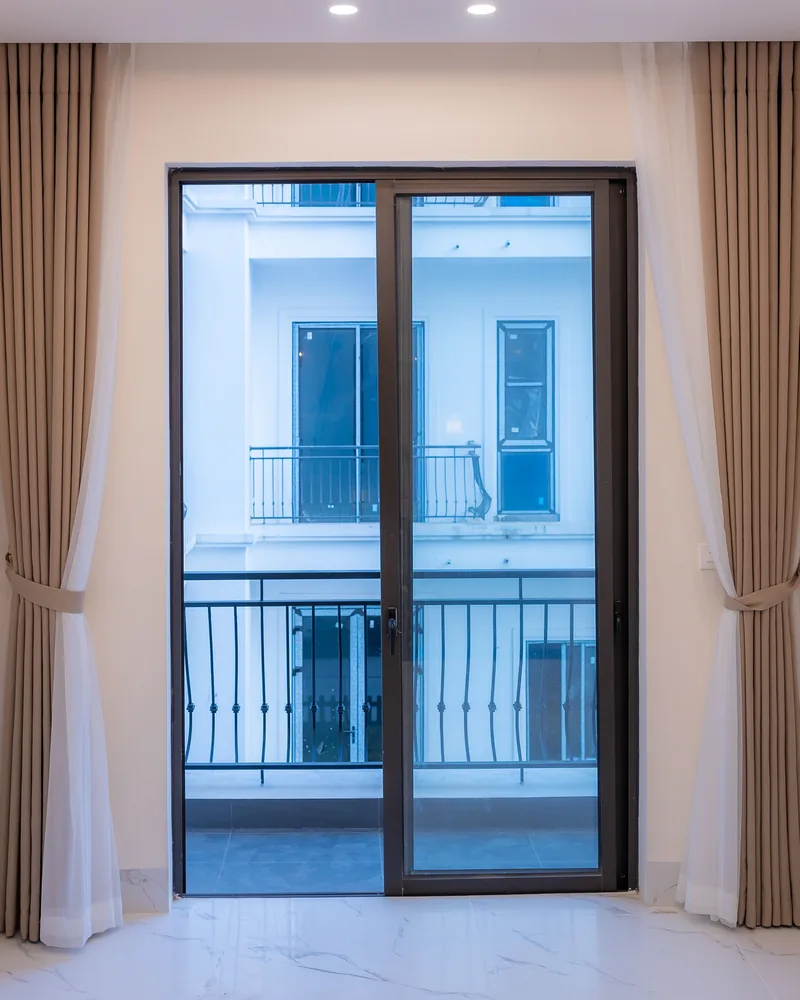 Curtains beside a sliding glass door onto an apartment balcony
