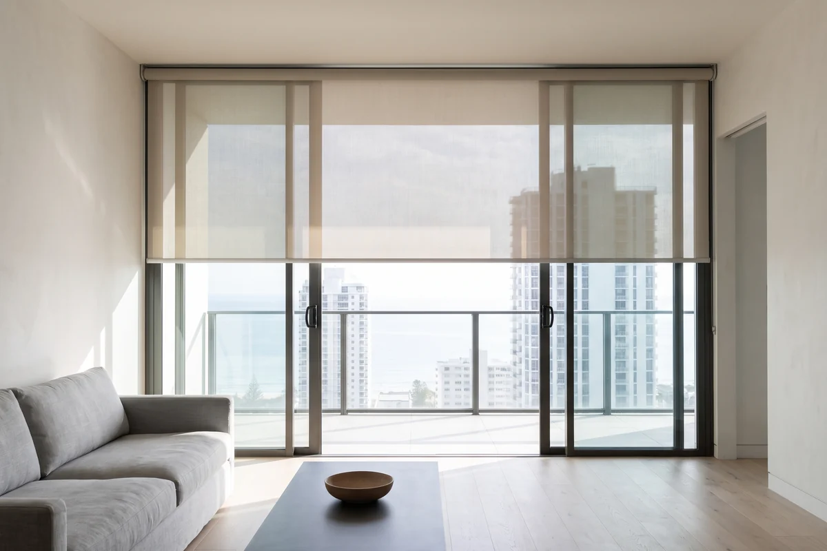 Looking out through a Gold Coast apartment window wall with a sunscreen roller blind half lowered
