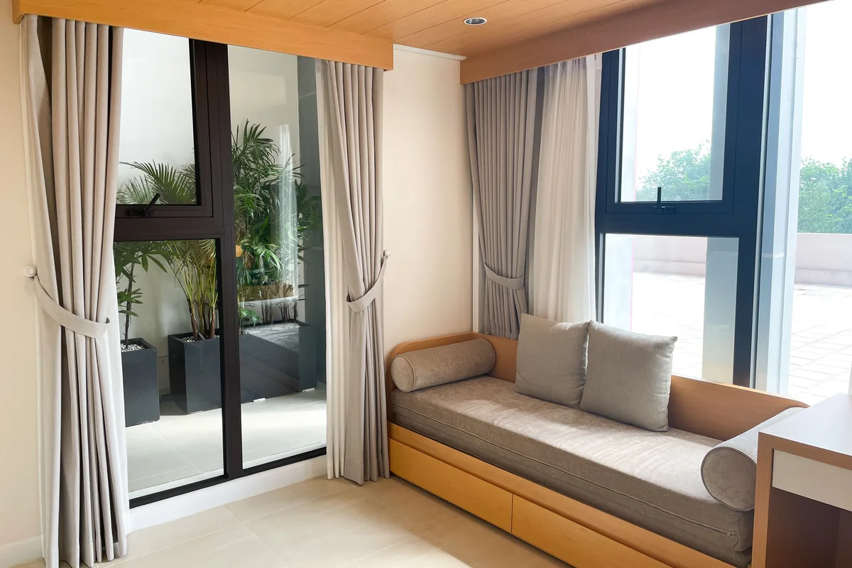 A corner window with a window seat and curtains drawn back at each facet