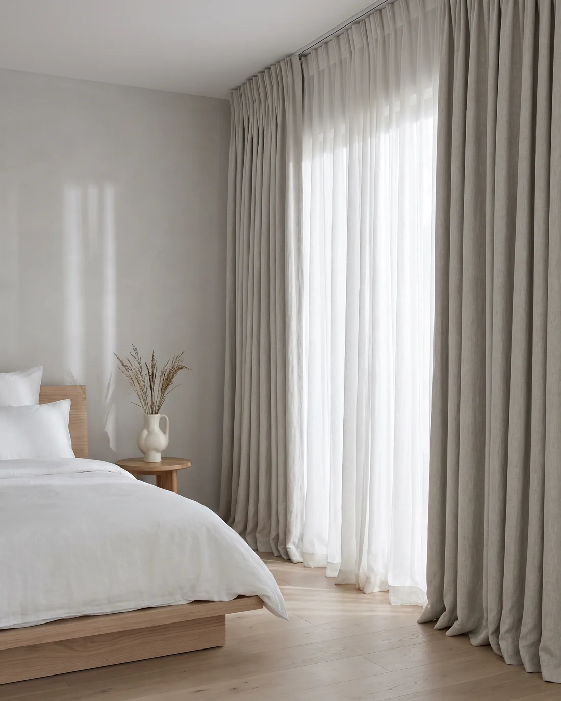 Bedroom with full-length pinch-pleat curtains and layered sheers