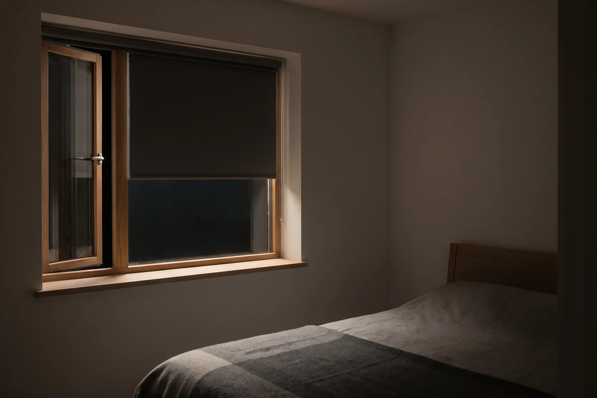 A bedroom window open to a night breeze with the blind lowered
