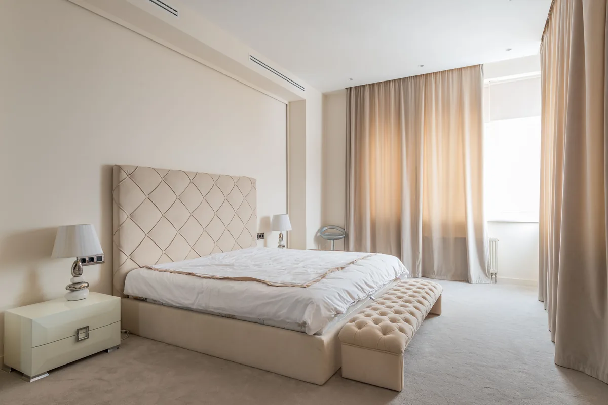 Pleated curtains hanging in even folds in a neutral bedroom