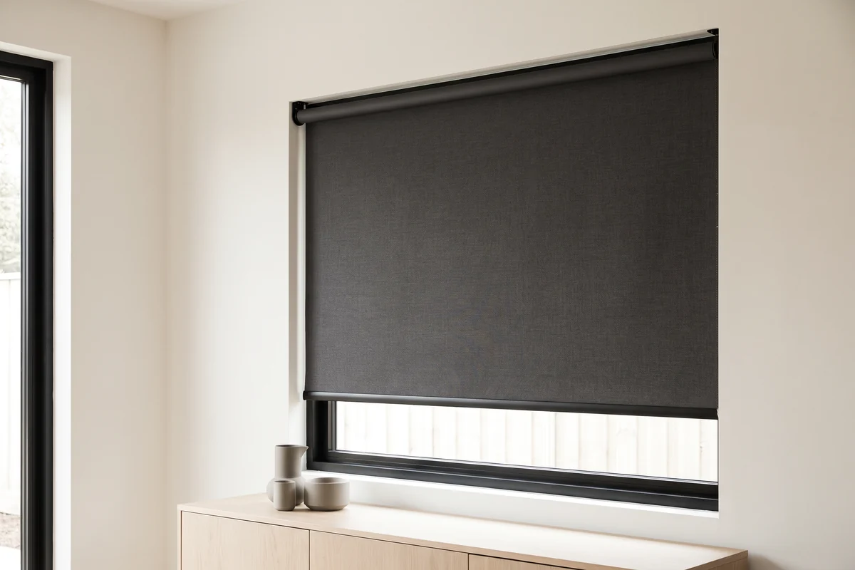 A charcoal roller blind lowered inside a black aluminium window frame