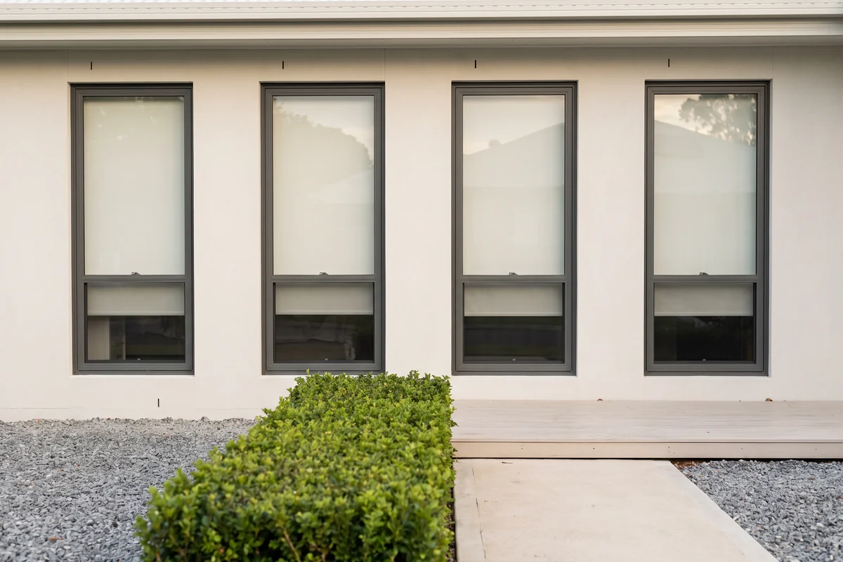 The front of a house from the street with every window showing matching pale blinds