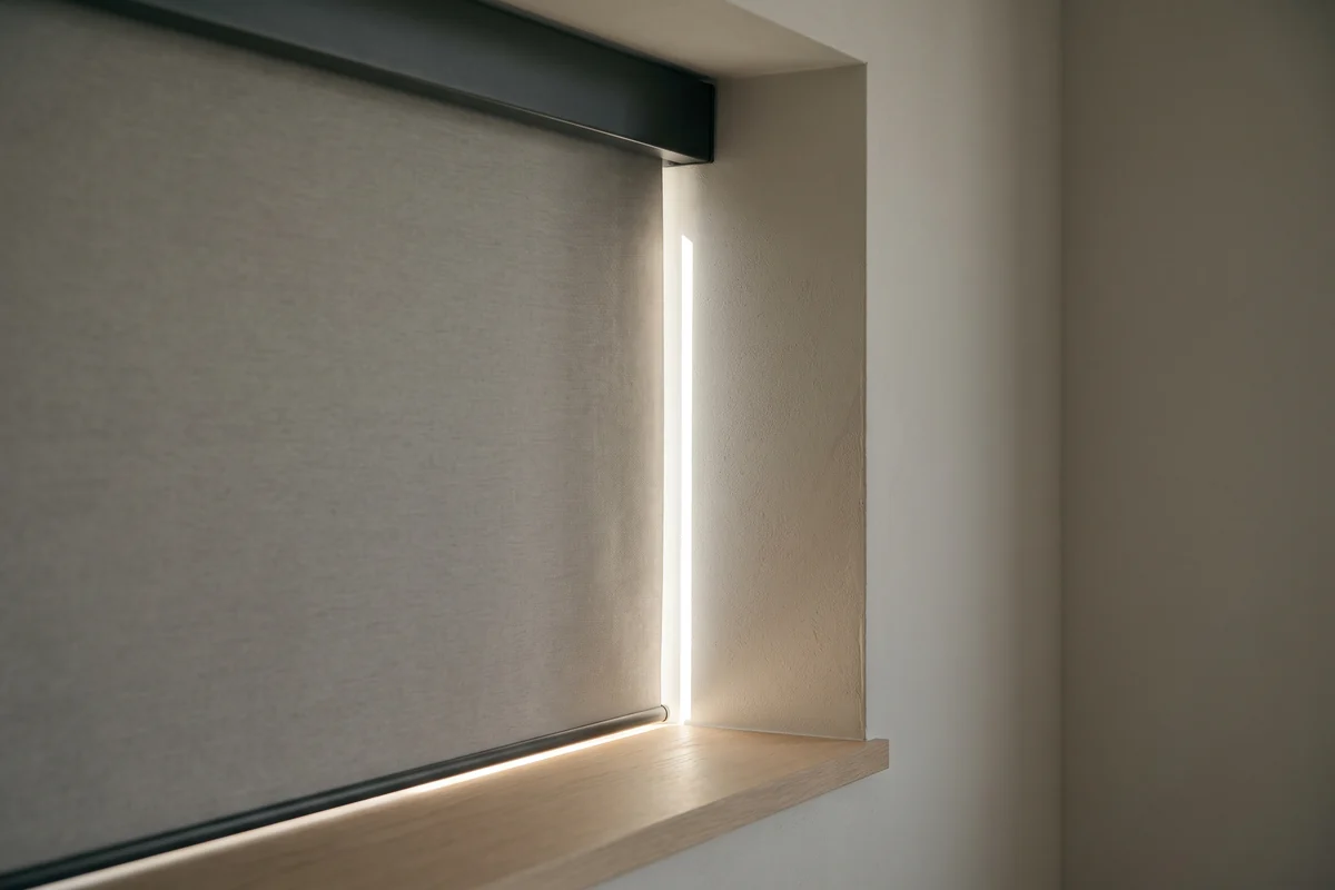 The vertical gap between a blind's fabric edge and the window reveal, with daylight cutting through it