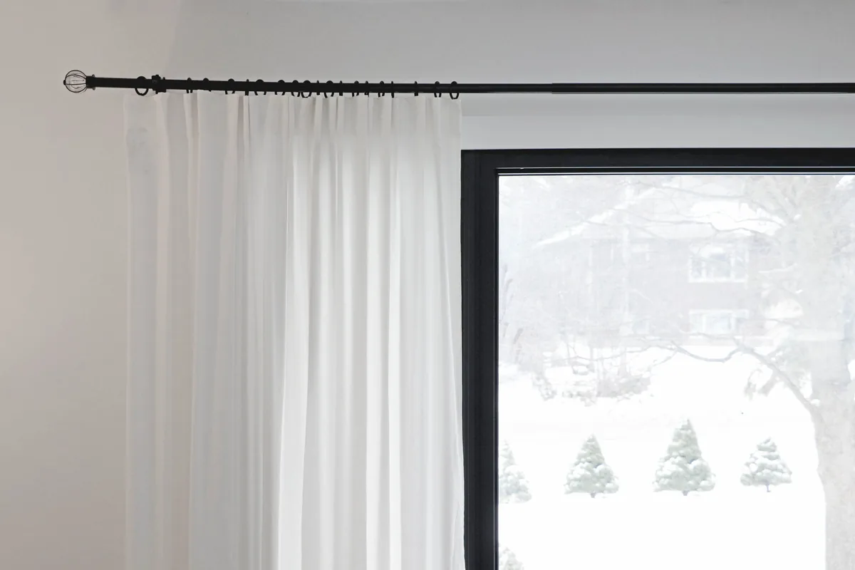 A metal curtain rod carrying rings above a window