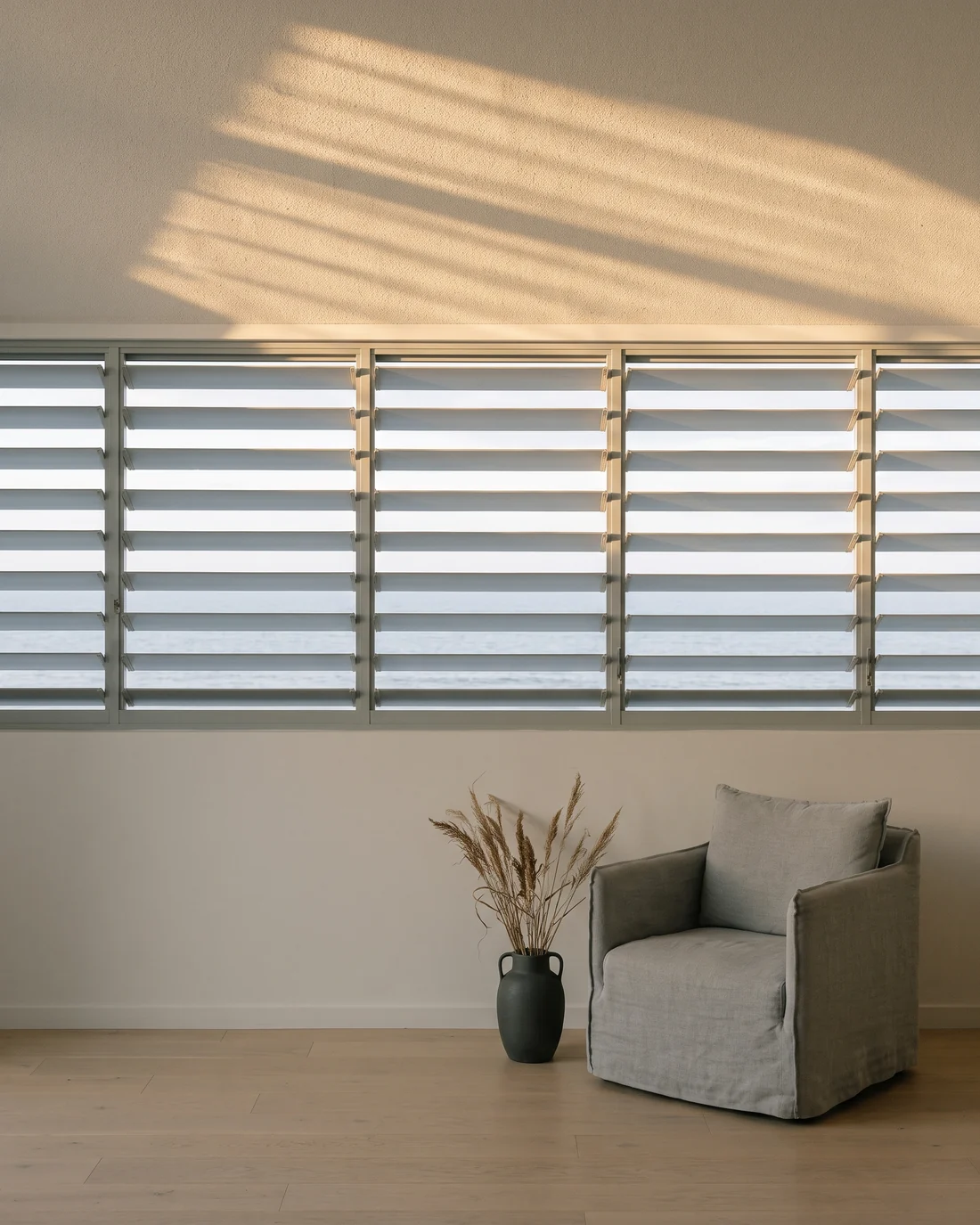 Venetian slats angled to throw low morning light onto the ceiling