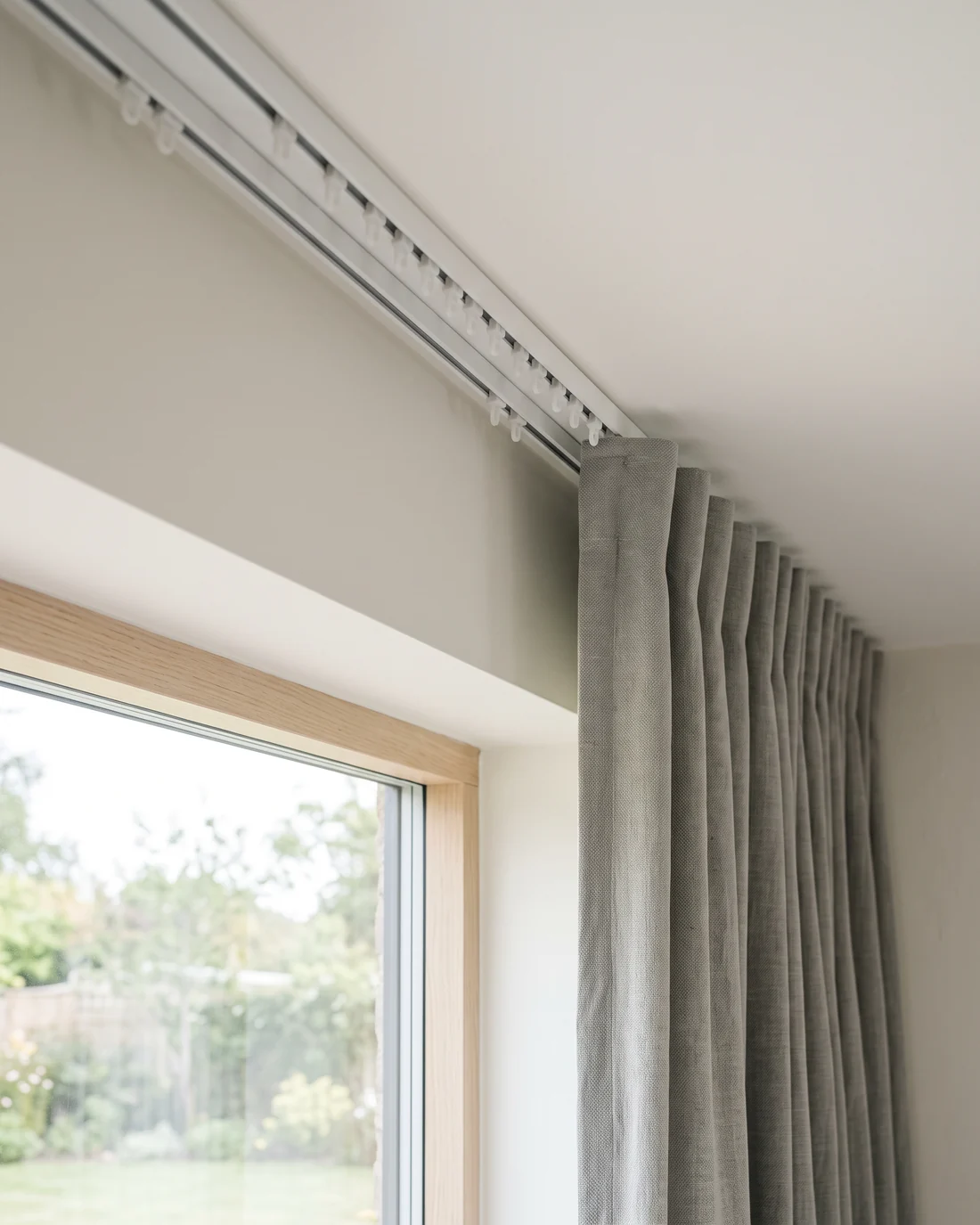 Detail of a ceiling-fixed curtain track with evenly spaced runners carrying the curtain heading