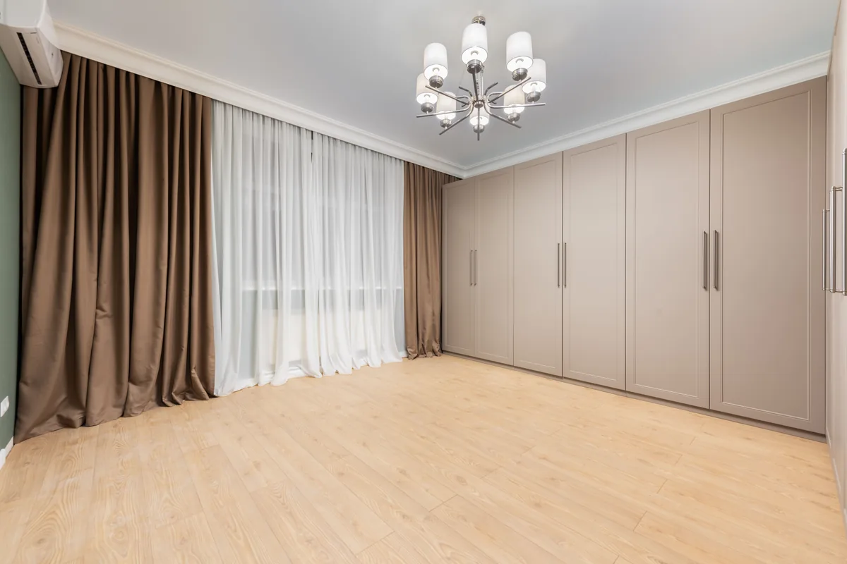 Curtains running from a ceiling-fixed track in a pale, minimal room