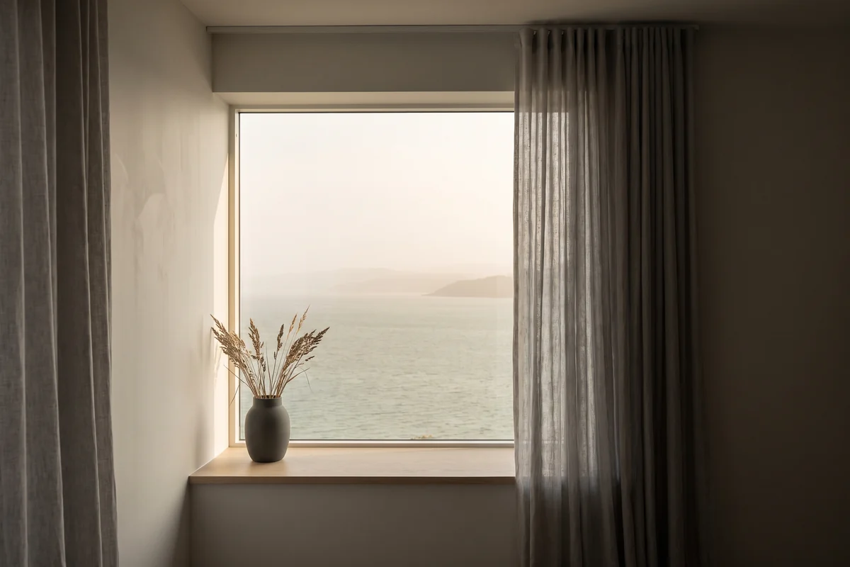 A coastal apartment window looking out over the water in humid afternoon light