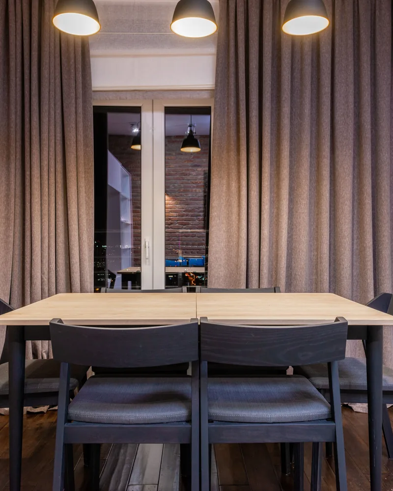Pleated curtains hanging in deep even folds beside a window
