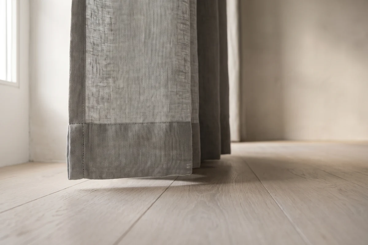 The hem of a floor-length curtain finishing just above the floorboards