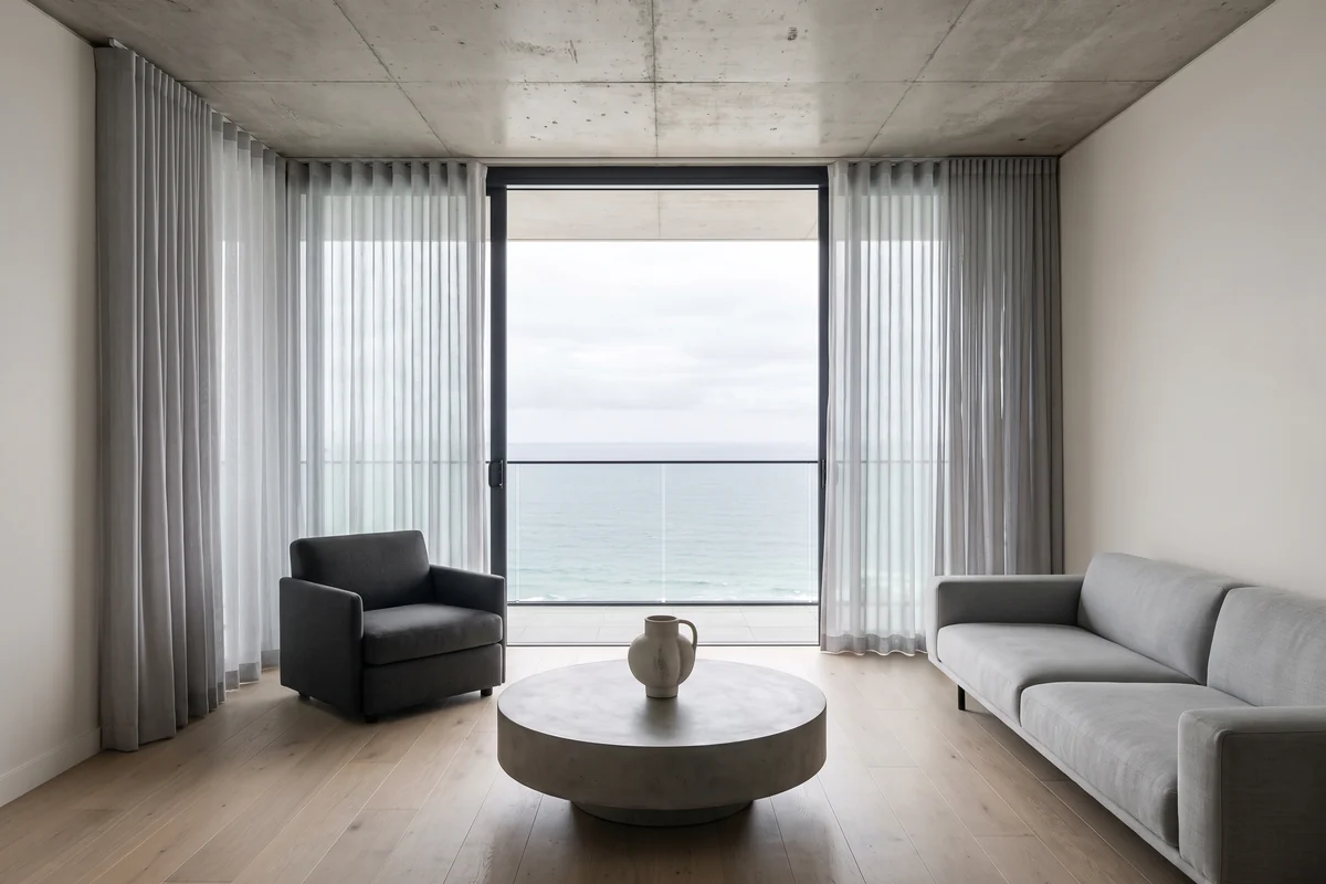 Sheer curtains split to both ends of a wall of glass in a beachfront apartment