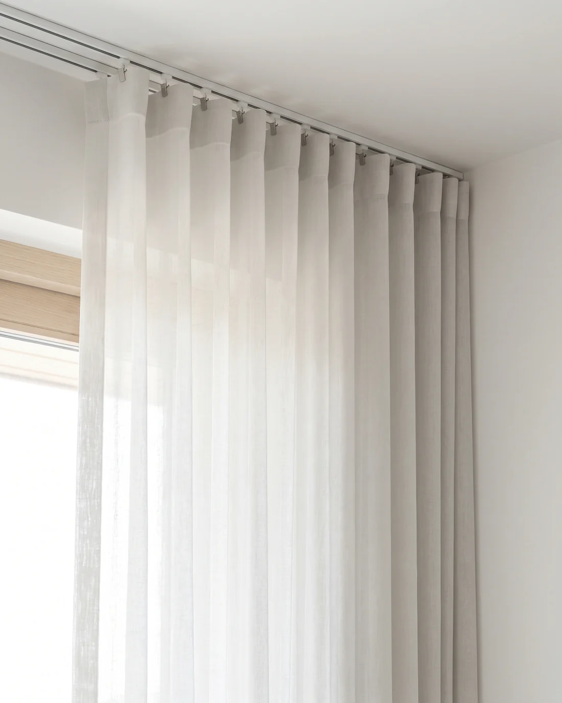 Sheer curtain heading clipped to evenly spaced carriers on a ceiling track