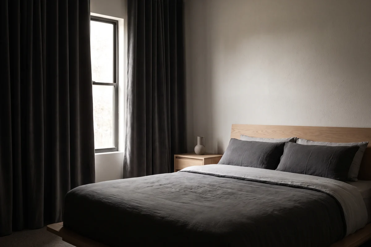 Dark-toned bedroom with heavy curtains hung beside the window