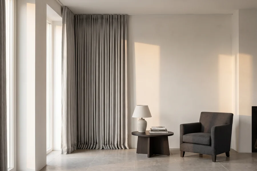 Full-length decorative curtains hung in a true column beside an armchair