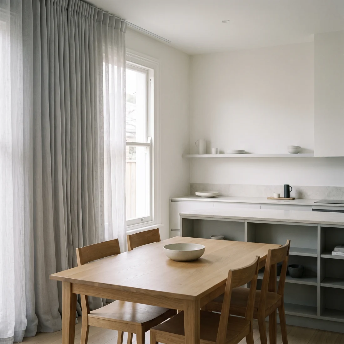 Dining and kitchen space with softly gathered curtains at the windows