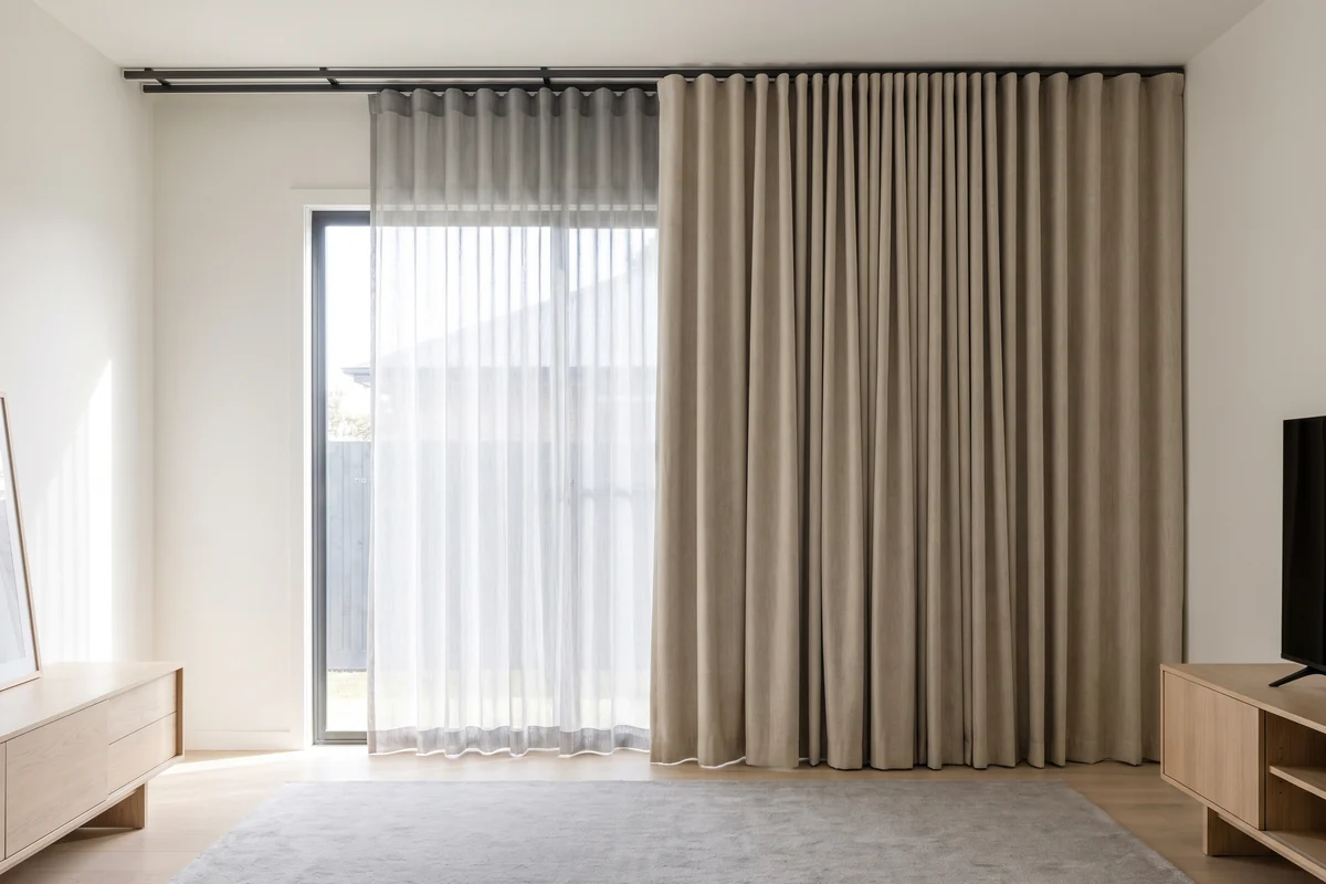 A double curtain track carrying a sheer on the rear channel and a blockout on the front channel above a living room window