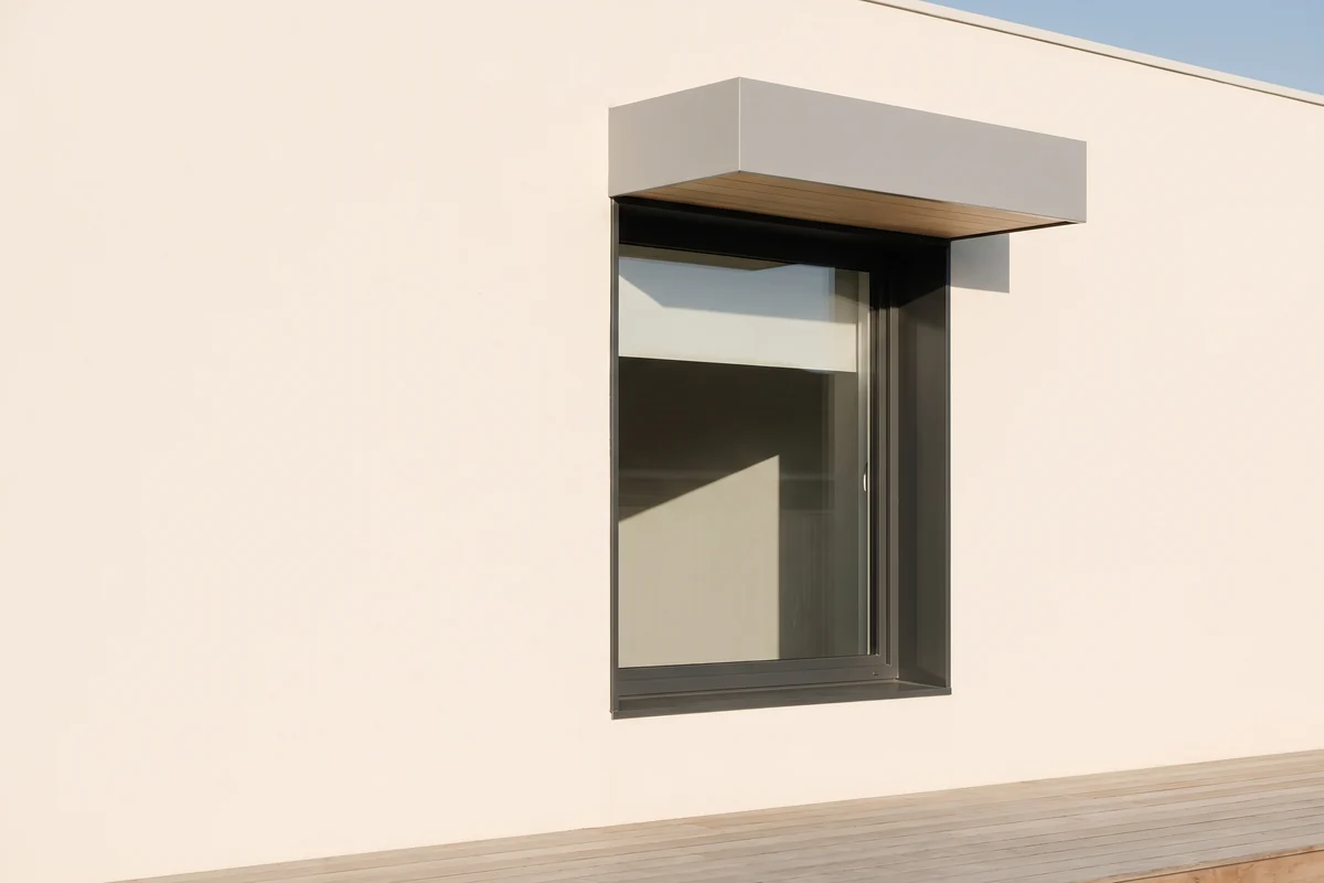 A fixed awning hood mounted permanently above a single window on an exterior wall