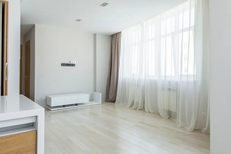 Floor-length sheer and blockout curtains layered across a wide living room window