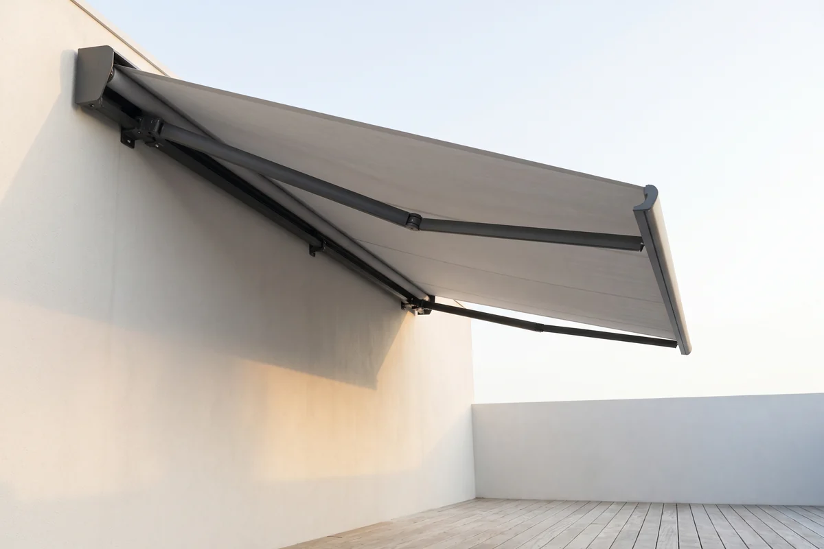 An extended folding arm awning, its front bar carried only by the cantilevered arms beneath the fabric