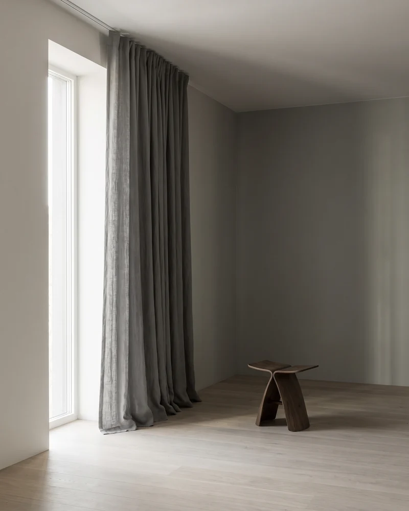 Full-height curtains hanging in a straight column at a tall window