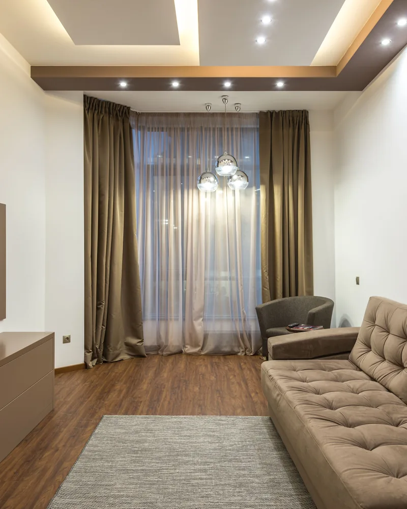 A media room with layered sheer and blockout curtains at the window