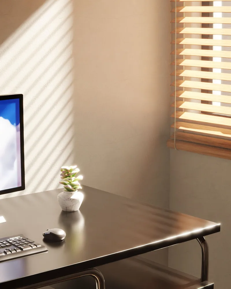 A home office desk beside a window with a blind half drawn