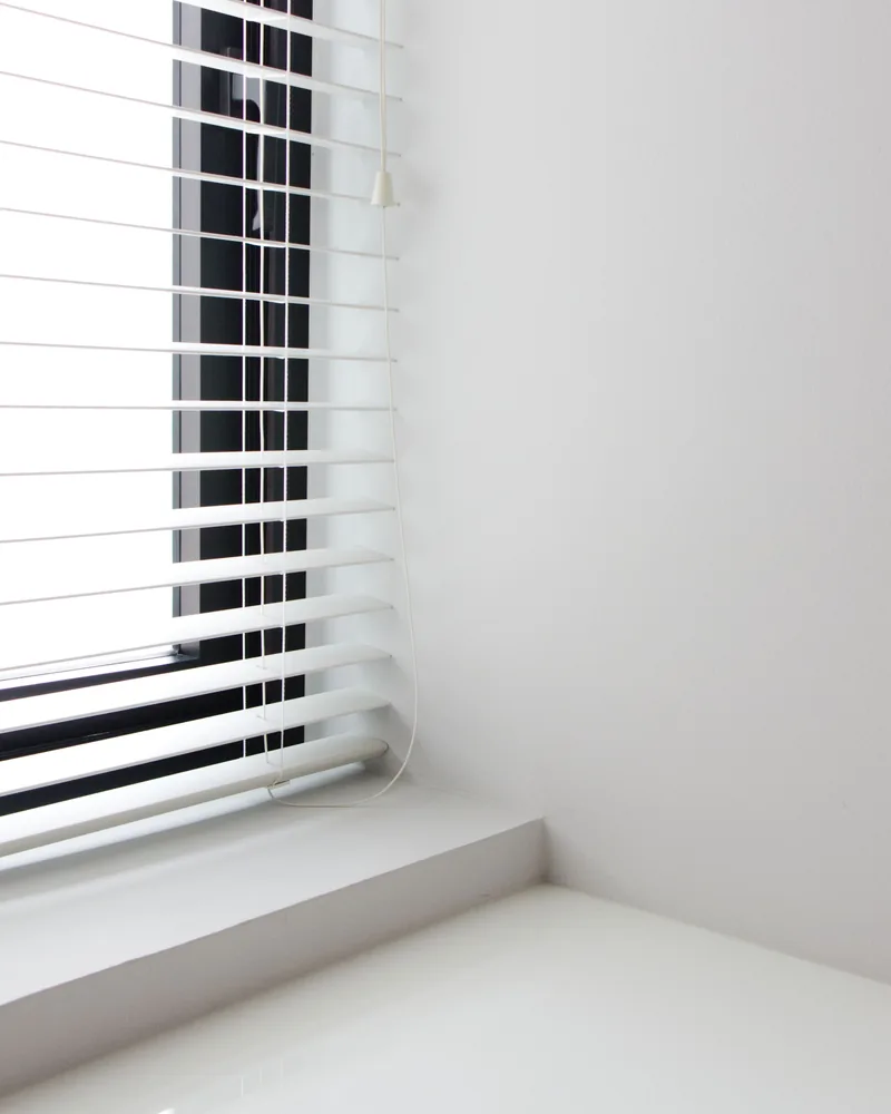 Daylight through a window blind in a plain white room