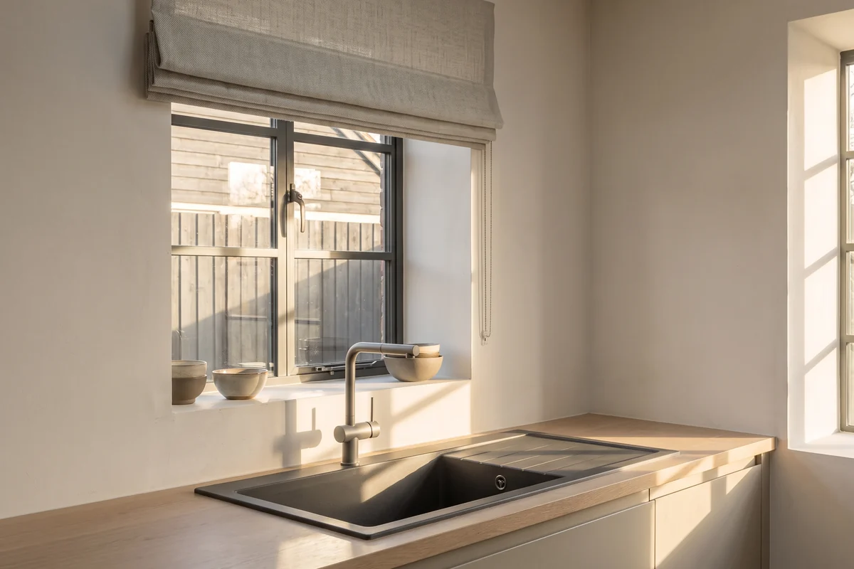 A kitchen window above the sink with afternoon light coming through