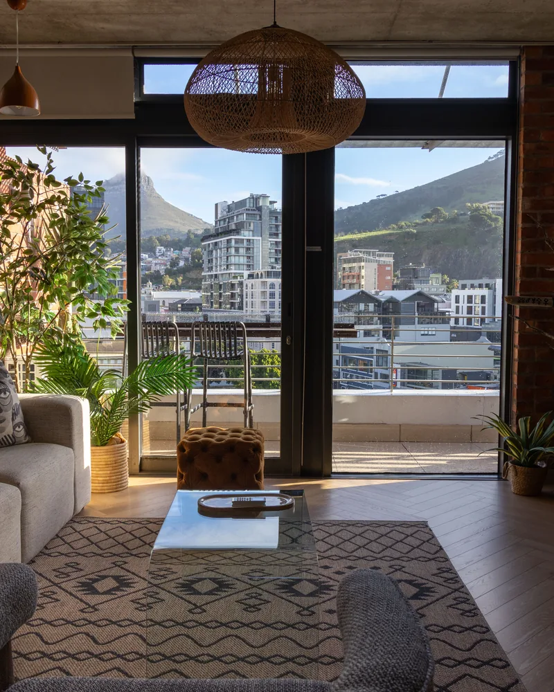 A living room opening onto a balcony through a wall of glass