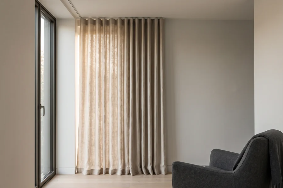 A natural linen curtain stacked back beside tall living-room glass