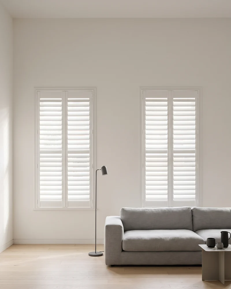 Two living room windows fitted with white shutter panels, louvres open level