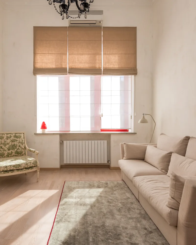 Sunlight across a living room window fitted with a blind