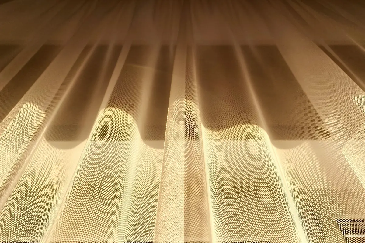 Light behind a fine open-weave screen fabric, showing the weave