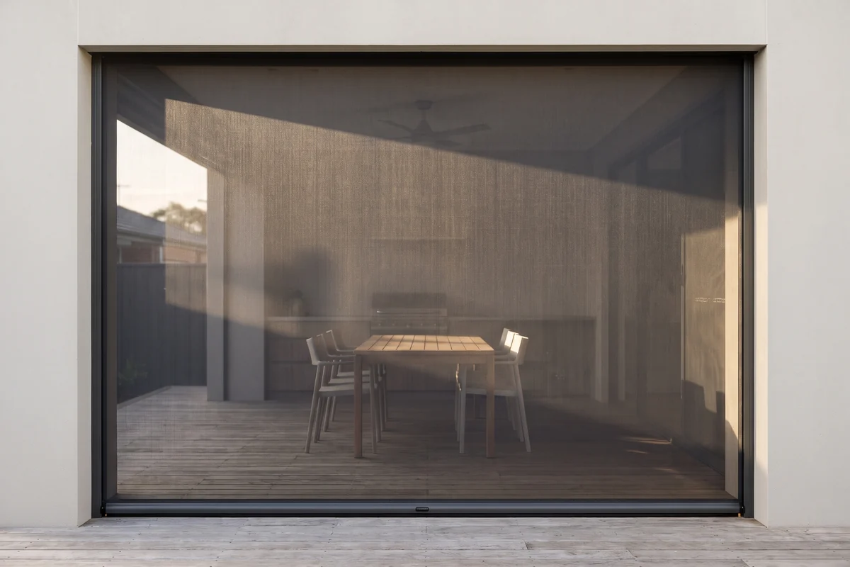 An outdoor blind lowered across an alfresco opening beside a dining setting