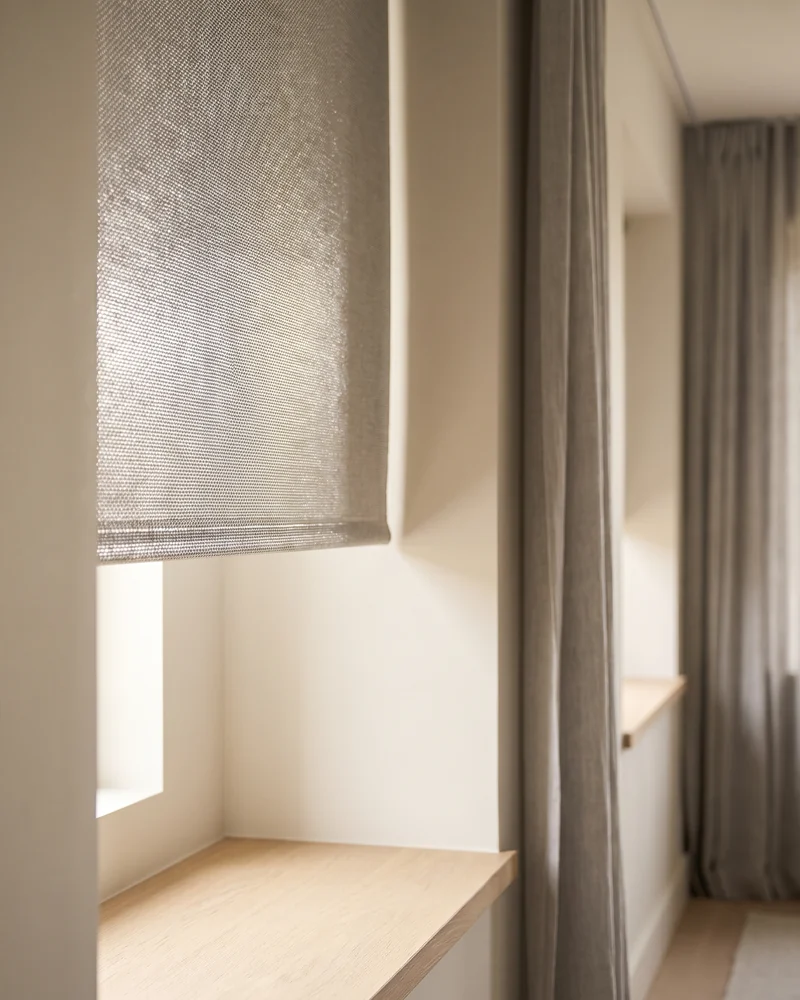 Metallised roller blind fabric with a reflective silver-grey backing at a sunlit window