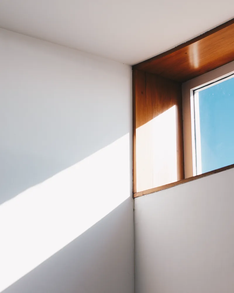 Sunlight falling across a plain interior wall beside a window