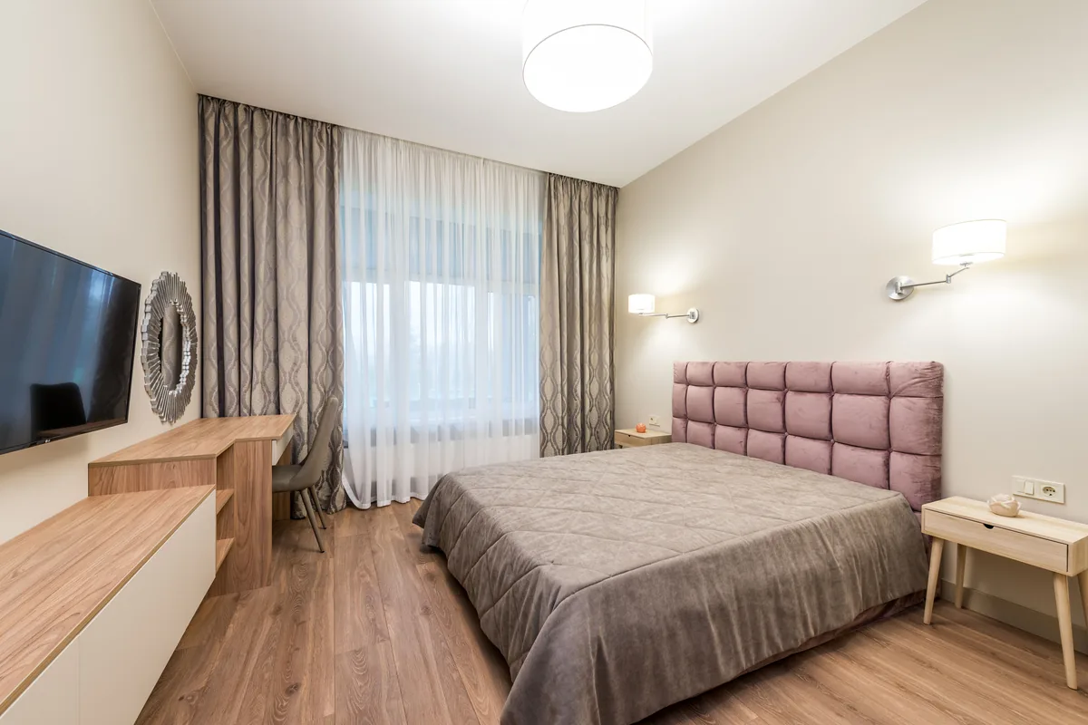 Bedroom curtains gathered into narrow folds over a sheer at the window