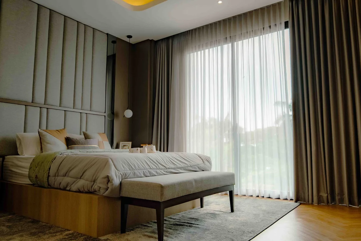 Neutral floor-length curtains hanging beside a tall window in a quiet room