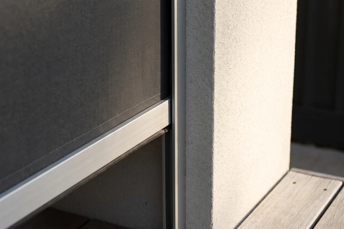 An outdoor blind with its fabric edge running inside an aluminium side channel