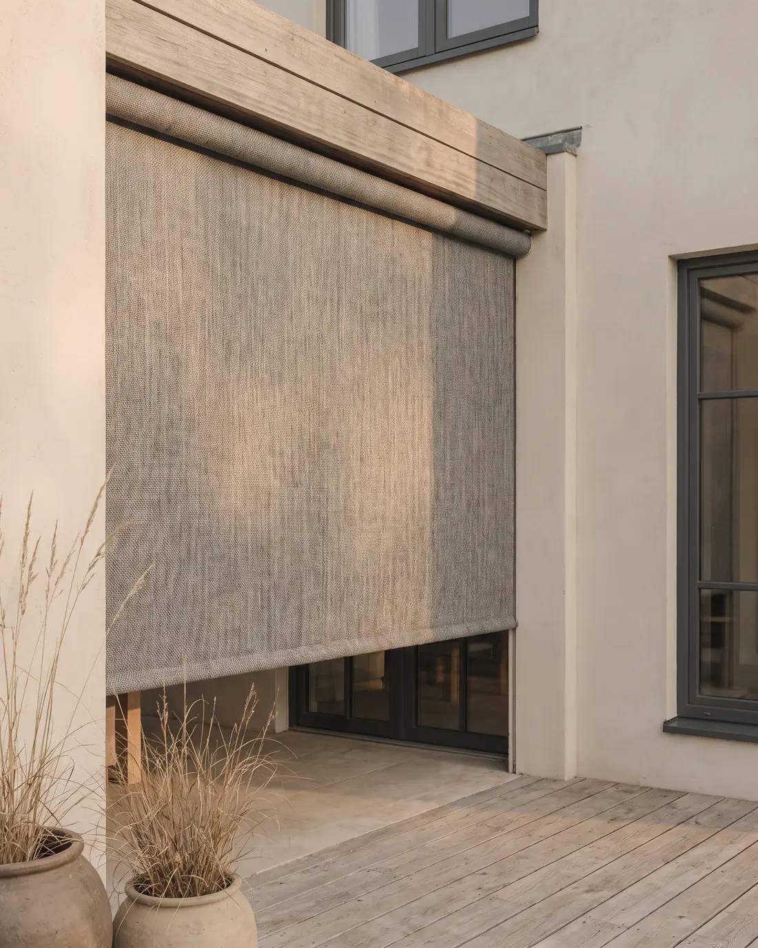 An outdoor blind rolled down over a patio in late afternoon sun