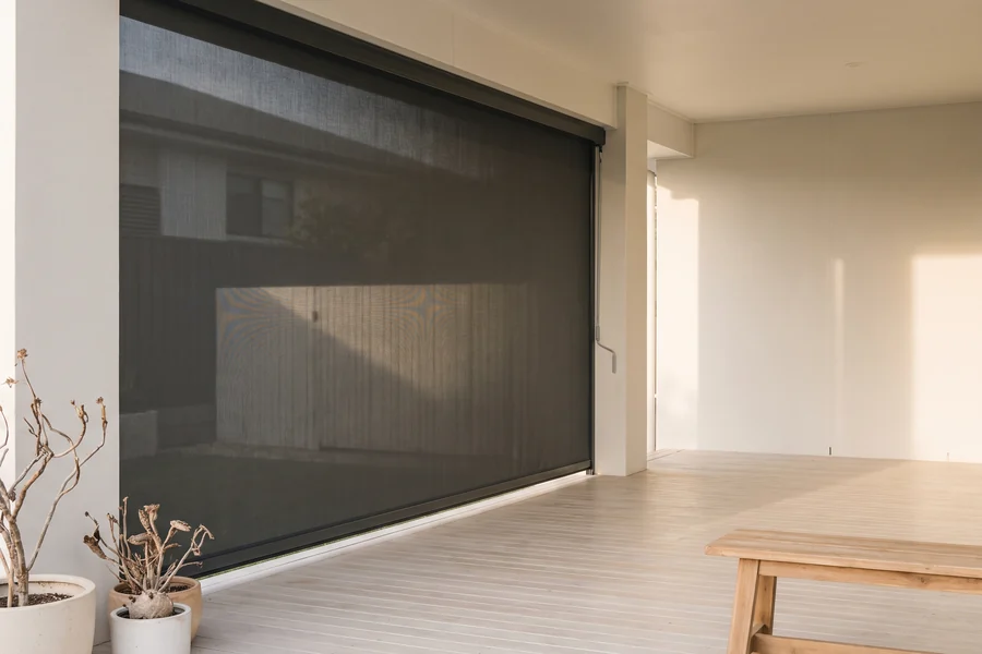 An outdoor blind lowered in side tracks across an alfresco patio