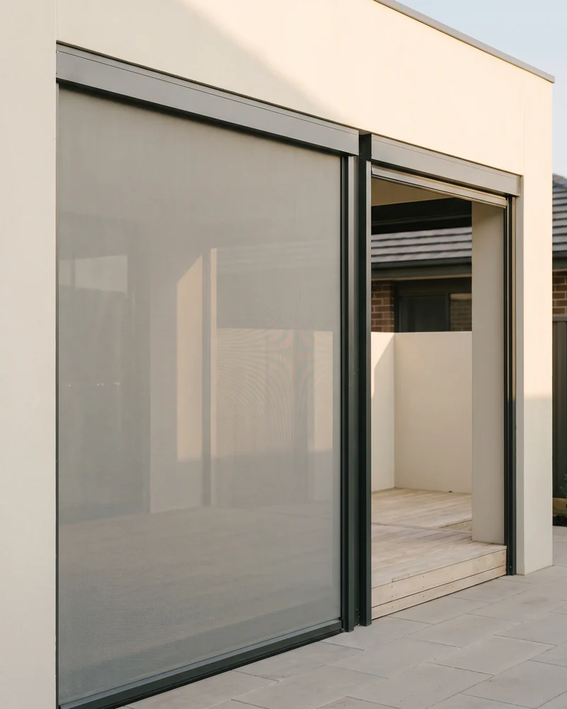 An outdoor roller blind lowered across an alfresco opening