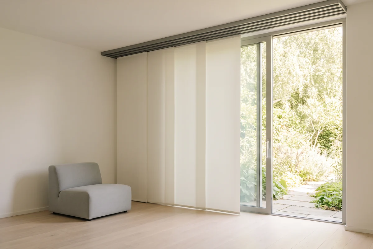 Flat fabric panels stacked on a multi-channel top track beside an open sliding glass door