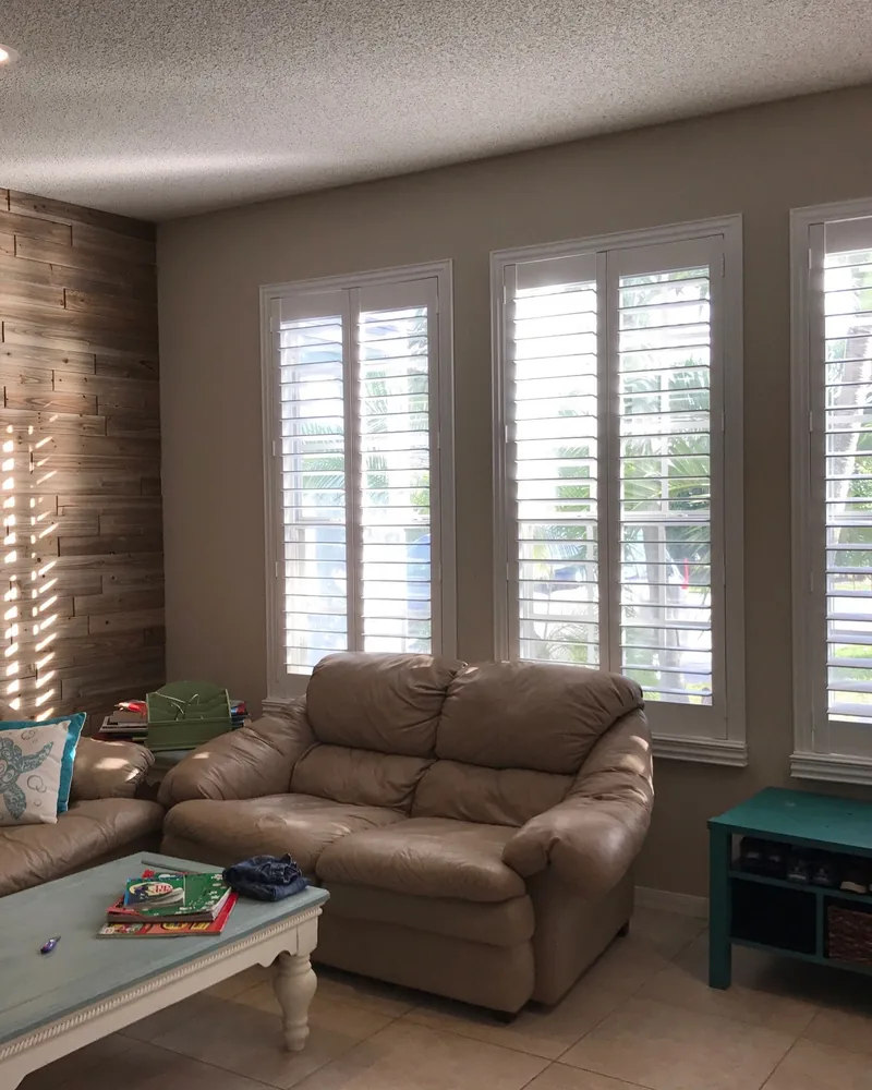 Fixed shutter panels across three tall living room windows