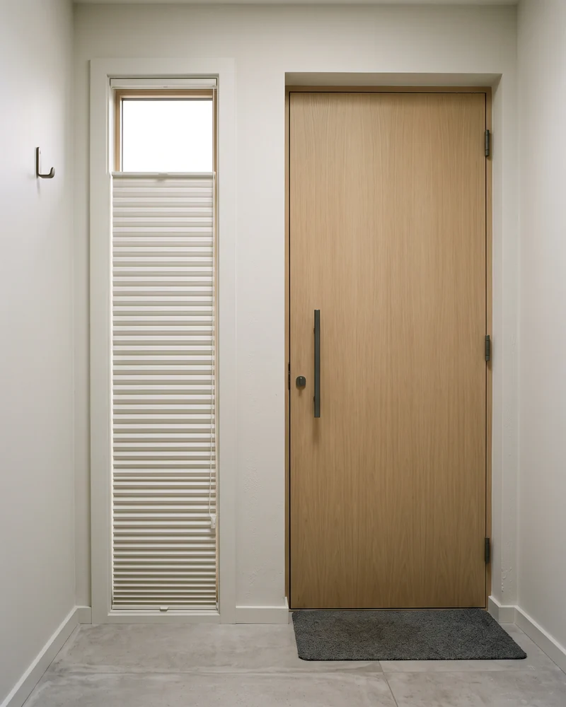 A pleated blind on a narrow window beside a door