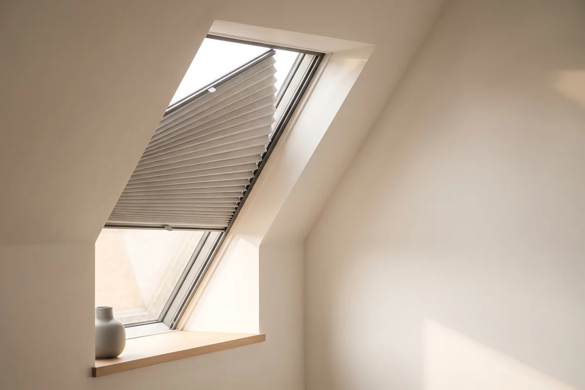 A pleated blind fitted to an angled window under a raked ceiling