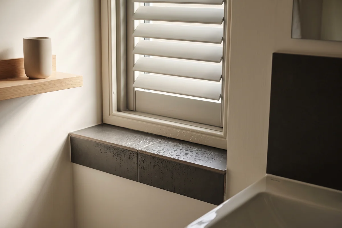 Polymer shutter louvres angled up on a bathroom window above a basin