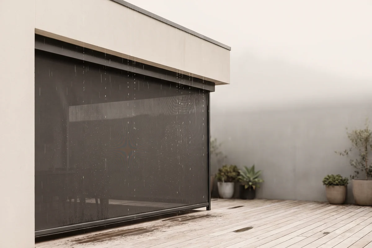 Rain falling past the edge of a covered alfresco area with blinds lowered
